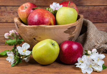 Differnt apples in vintage wooden bowl, apple flowers and leaves