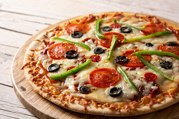 Traditional supreme pizza on rustic wooden table	