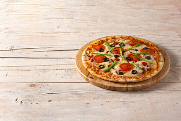 Traditional supreme pizza on rustic wooden table. Copy space
