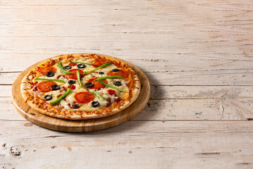 Traditional supreme pizza on rustic wooden table. Copy space