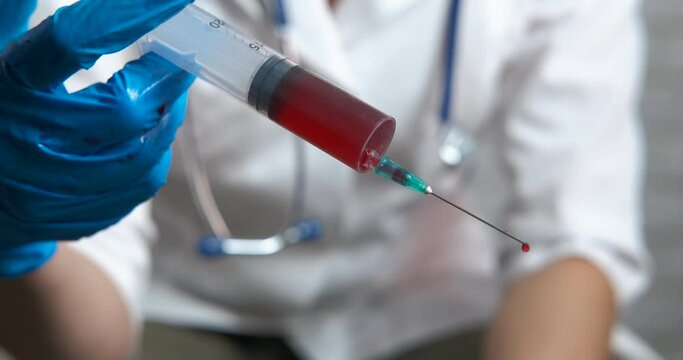 Medical tests with venous blood. A medical worker in latex gloves hold a syringe with venous blood in the lab.