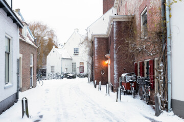 A wintry cityscape of the medieval city of Amersfoort in the center of the Netherlands. Buildings and streets are covered with snow.	