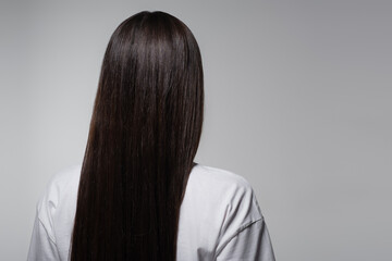 back view of young woman with smooth long hair isolated on grey