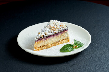 Cheesecake with pear and blueberries in a white plate on a black background
