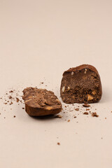 Chocolate truffle halved in two pieces on a beige background