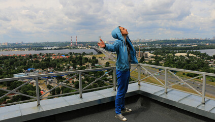 a guy on the roof of a multi-storey building with outstretched arms against the background of the urban landscape. Kyiv, Ukraine,