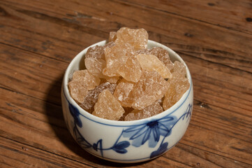 The rock sugar in the container is on the wood grain table