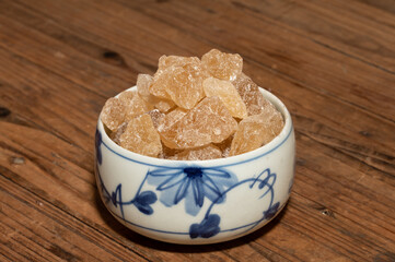 The rock sugar in the container is on the wood grain table