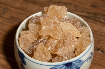 The rock sugar in the container is on the wood grain table