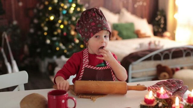 Cute blond child, baking christmas cookies at home, having fun
