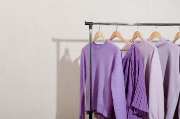 Fashionable tops in trendy purple, very peri, lavender colors hanging on a shopping rail. 