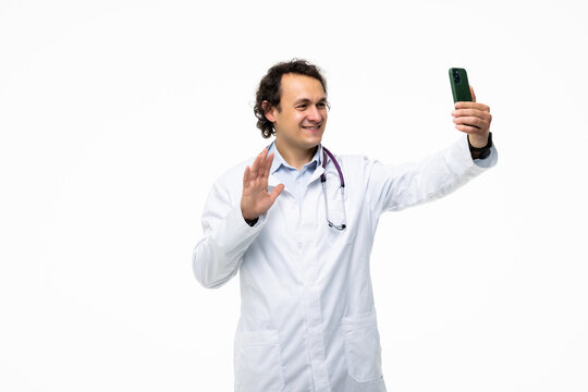 Confident and successful doctor or medic taking a selfie with smartphone on white background