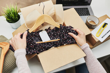 Business owner packing online order to delivery to customer. Preparing parcel box with clothes...