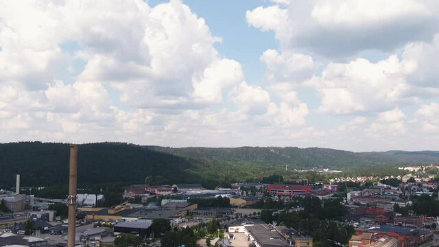 Industrial chimney and living buildings of small town in Sweden, aerial tilt down shot