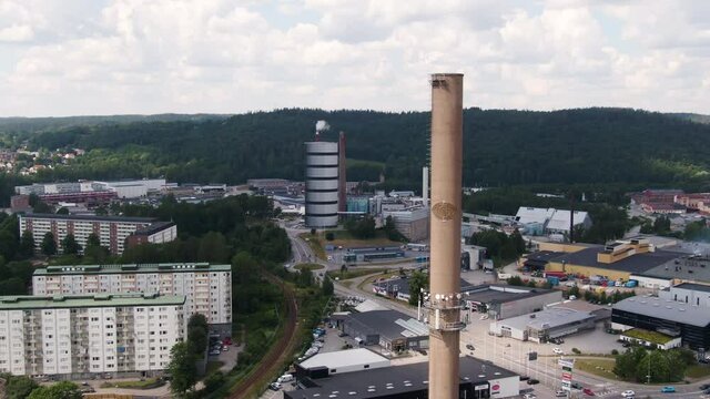 Apartment buildings and massive industrial chimney in Swedish city, aerial drone view