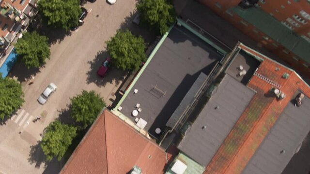 Swedish town building rooftops with city street traffic, aerial top down fast flying view