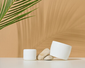 white round plastic jar for cosmetic products on a brown background. Palm leaf shadow. Blank for branding products, mock up