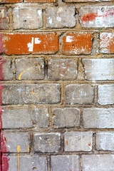 Brick wall with some bricks pristine and others marred, smudged, or chipped