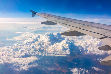 View from the airplane window at a beautiful cloudy sky and the airplane wing