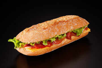 Baguette sandwich with ham, smoked sausage, cheese, and green salad on a black background.