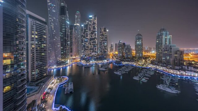 Dubai marina tallest skyscrapers and yachts in harbor aerial all night timelapse.