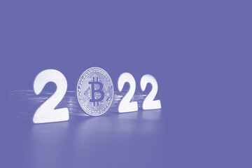 Bitcoin 2022 sign. Single Bitcoin coin next to the numbers with copy space for text toned in very peri color of the year. Price, future value of BTC crypto prediction concept.