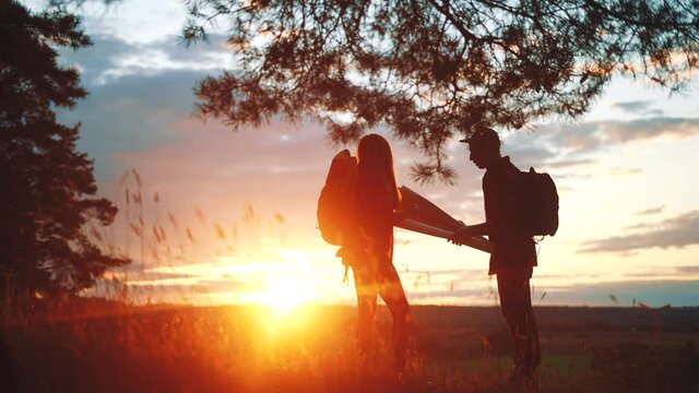 travel navigation. team hikers silhouette a stand on the top of the mountain finding path on paper map. happy family hikers in the park travel. sunlight freedom team silhouette travel concept