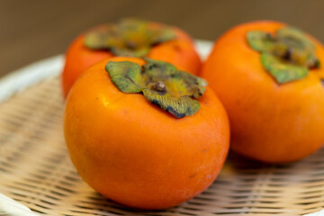 竹ザルの上のおいしそうな柿にクローズアップ