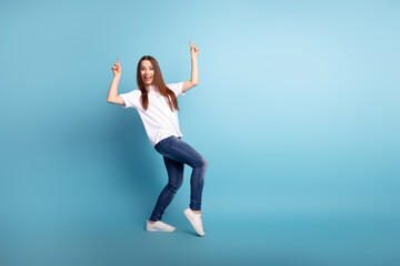 Full body photo of young lovely lady indicate fingers empty space promo dancing isolated over blue...