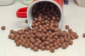 ready breakfast round chocolate flakes poured from a red mug on the table
