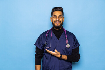 Young male doctor showing and presenting something with hand, isolated on blue background with copy space on right side