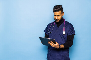 Naklejka na ściany i meble Indian male doctor holding a blank clipboard and looking at him. Surgeon concept.