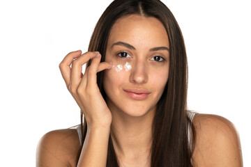 a young beautiful woman applies facial  cream