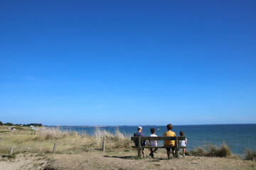 famille assise sur un banc face à la mer