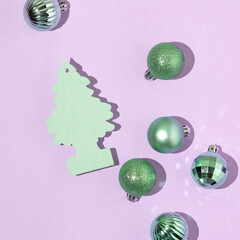 Creative layout with green Christmas tree card and green baubles on pastel purple background. 80s...