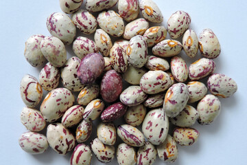 A pile of seeds of colorful dragon tongue beans, white background
