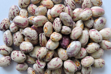 A pile of seeds of colorful dragon tongue beans, white background
