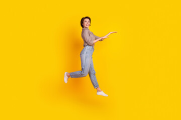 Fototapeta na wymiar Full size profile side photo of young cheerful girl demonstrate prodcut promotion ads jump isolated over yellow color background