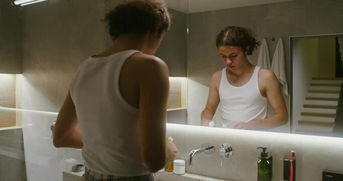 Young man squeezes toothpaste onto a toothbrush and begins to brush his teeth