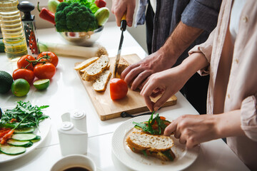 Close-up portrait of a couple's hands preparing breakfast together. Healthy sandwich.