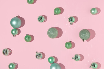 Creative layout with green Christmas baubles on pastel pink background. 80s or 90s retro fashion aesthetic concept. Minimal New Year or Christmas celebration idea.
