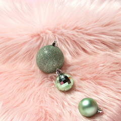 Creative layout with three green Christmas baubles on pastel pink faux fur background. 80s or 90s...