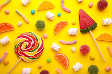 Colorful candies lollipops and jelly on yellow background. Top view. Sweets