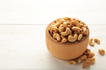 Cashew nuts on wooden bowl on white background. Top view.