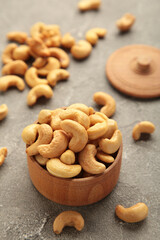 Cashew nuts on wooden bowl on grey background. Top view.