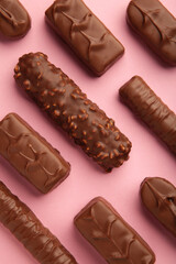Mix of chocolate bars on pink background. Top view.