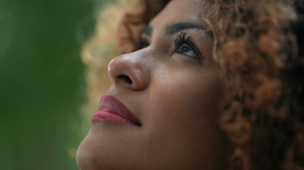 African woman taking a deep breath outside in nature looking up at sky smiling feeling free
