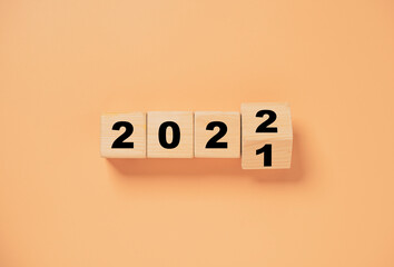 Wooden cube block flipping from 2021 to 2022 on orange background , preparation for merry Christmas...
