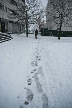 Person walking and leaving footsteps in the snow behind him while it is snowing