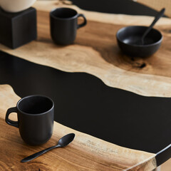 Obraz na płótnie Canvas Minimalist composition on the design wooden and epoxy table with black teapot, cups and spoon. Modern dining room interior. Details. Template...